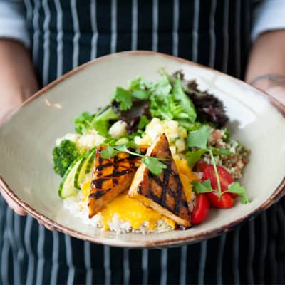 Soy grilled tofu, tabbouleh, pineapple salsa, roasted cauliflower and broccoli, tomatoes, cucumber, fresh greens, jasmine rice, miso carrot ginger sauce.