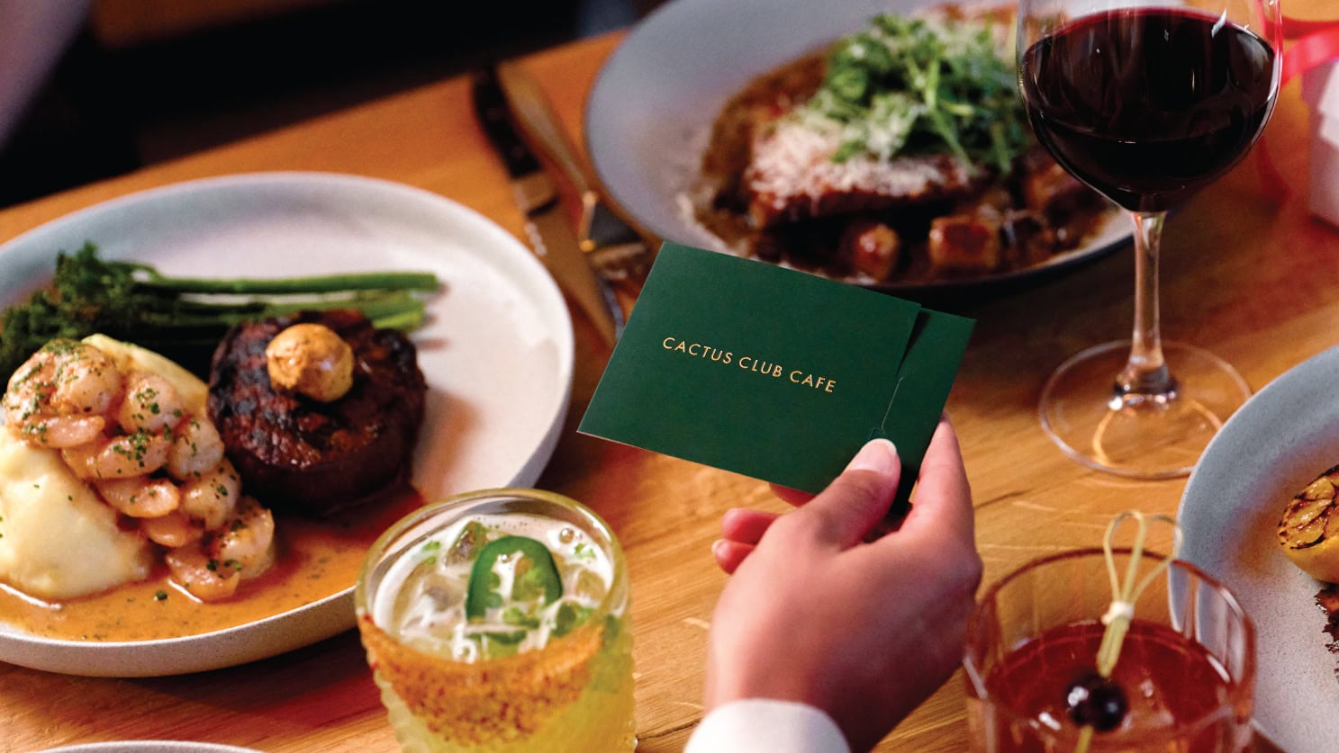 Table full of food and drinks with a person holding a physical gift card.