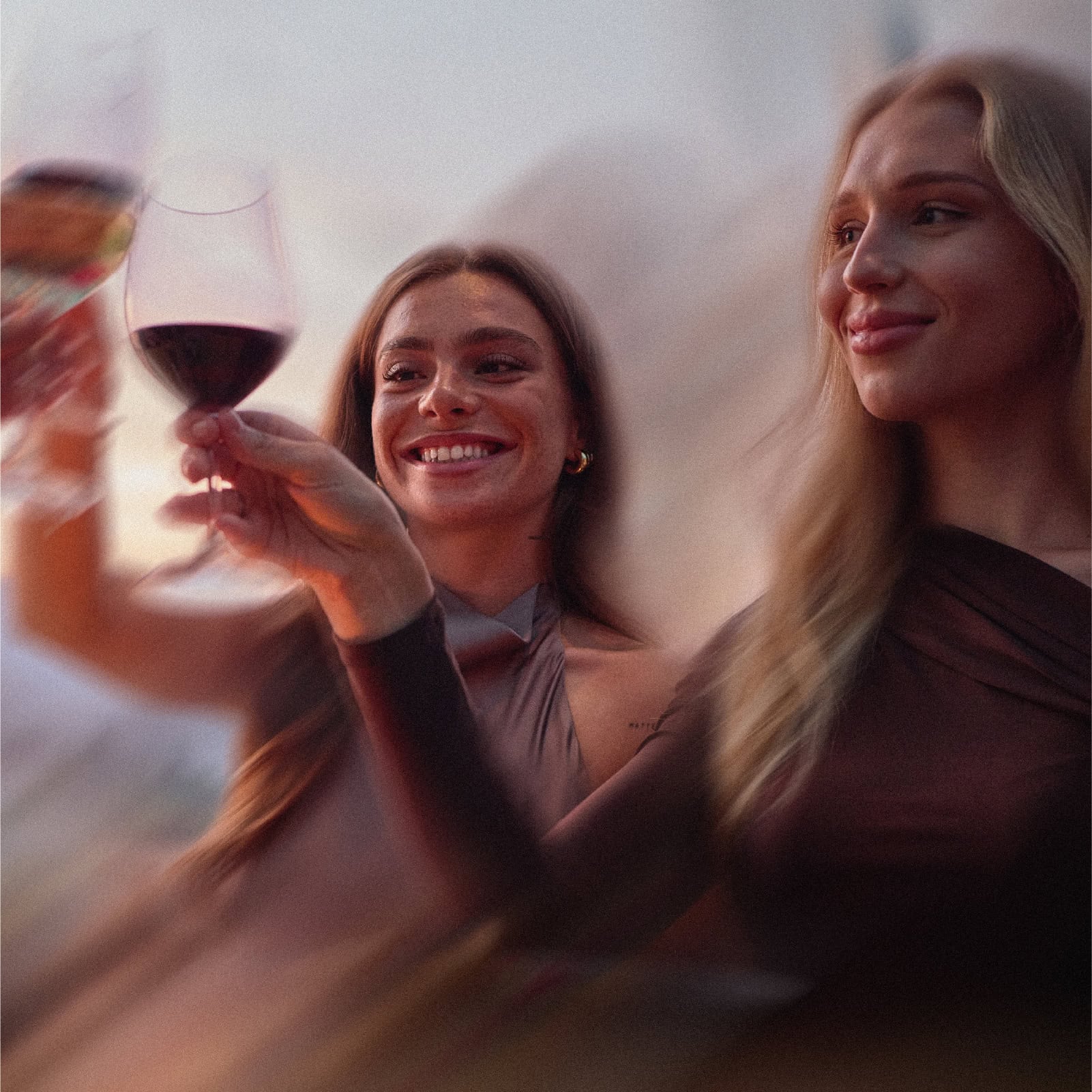 Two women raising their glasses, about to clink them together in a cheers.