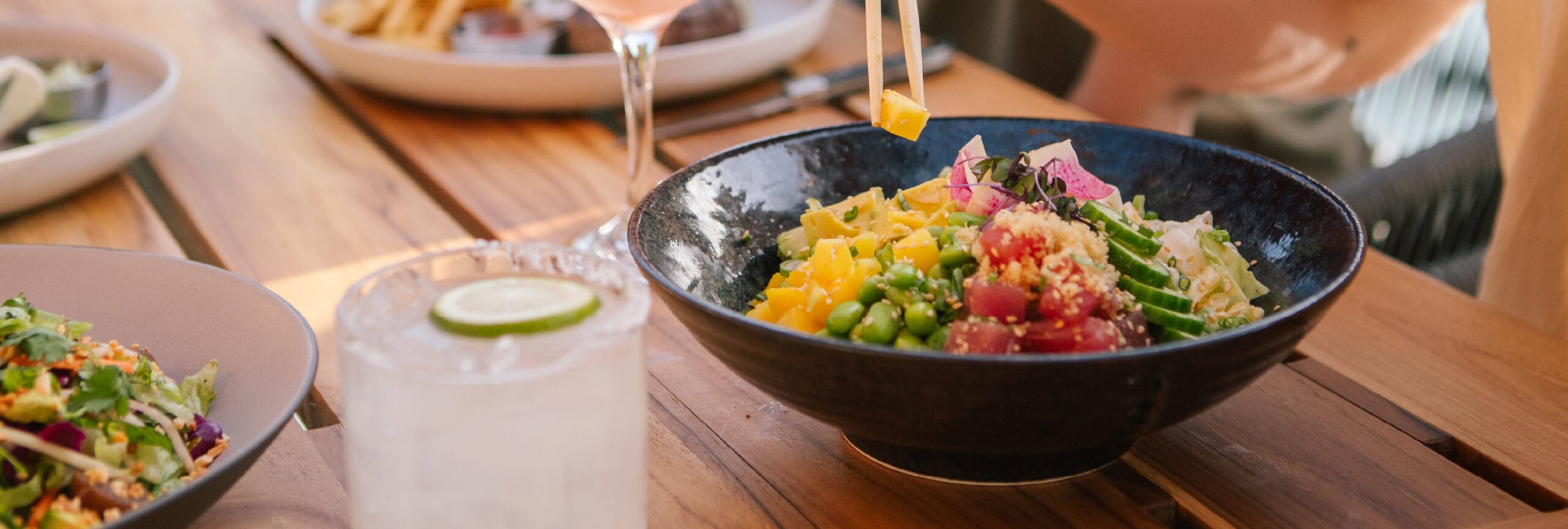 A spread of food and drinks on the table with a focus on the Tuna Poke Bowl