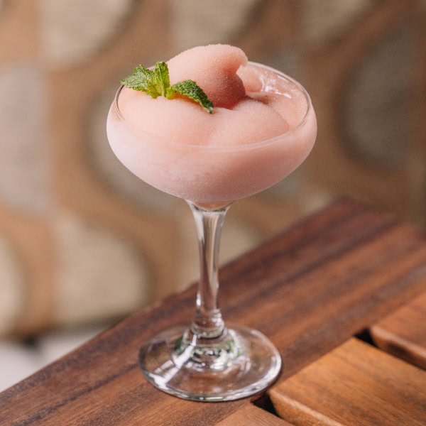 Frozen pink slush drink in a coupe glass